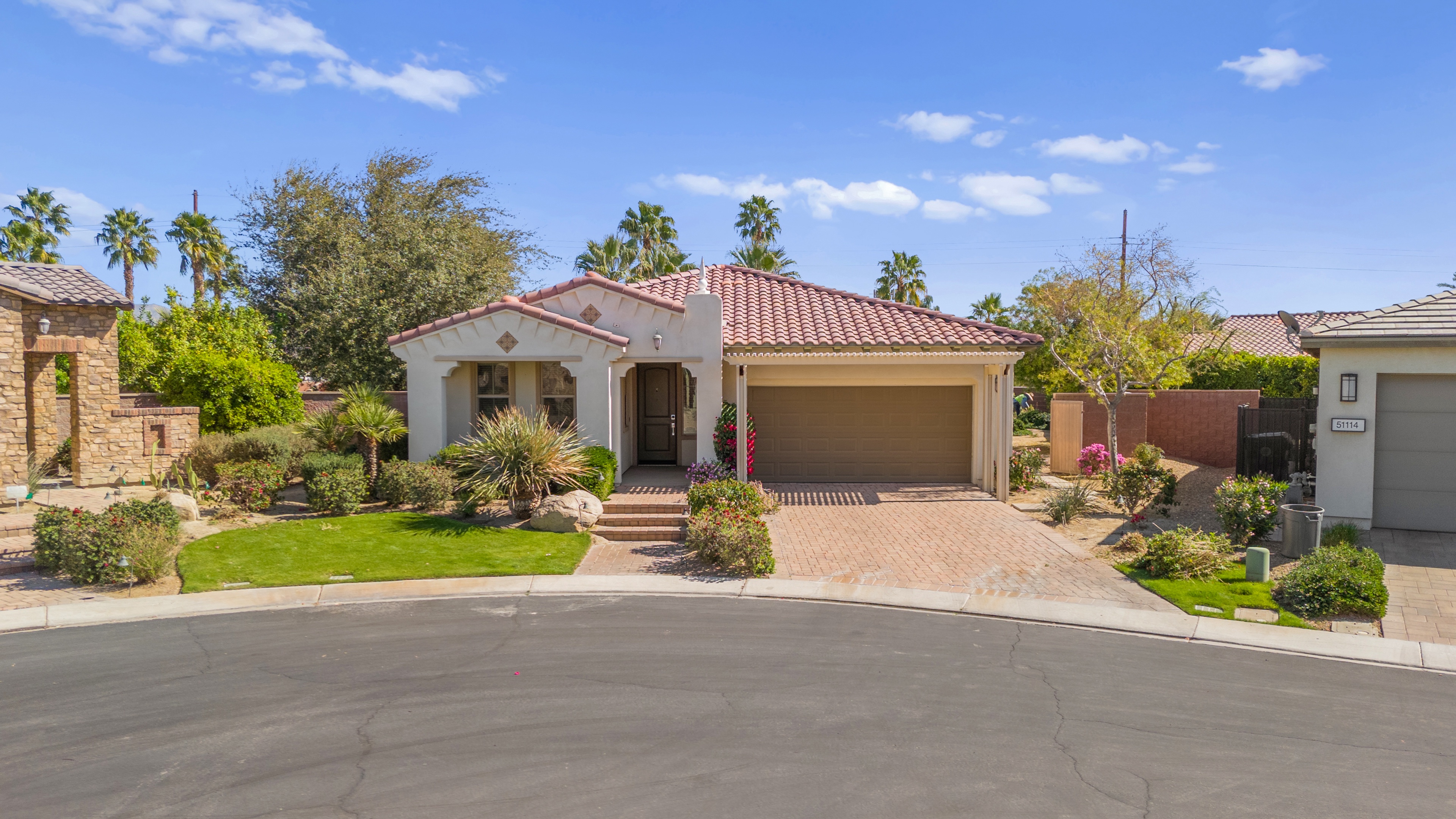 Spanish-style home with desert landscaping and palm trees